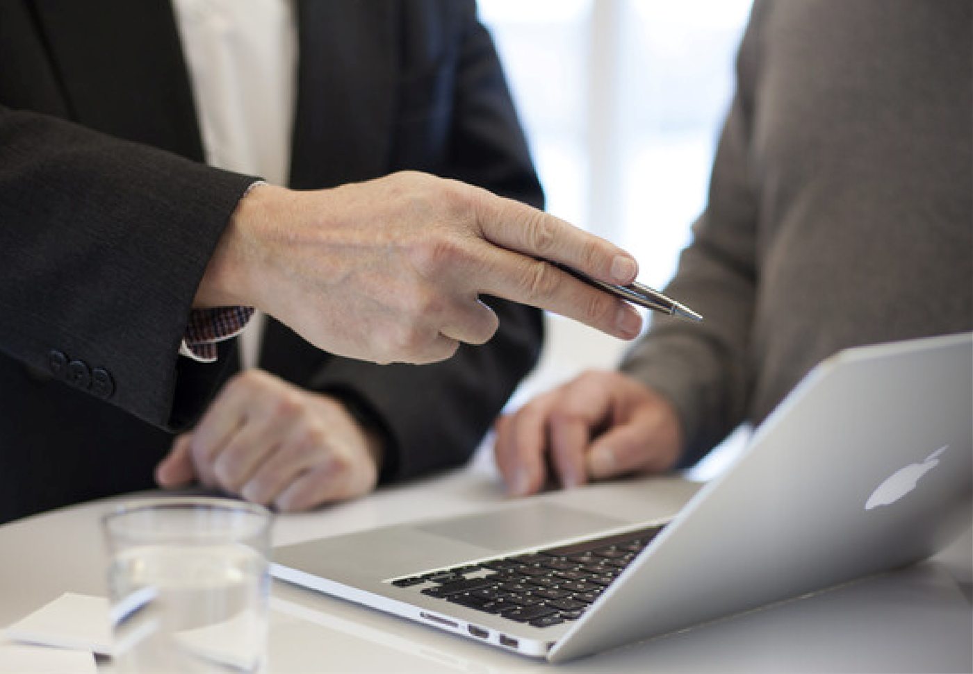 Consultor señalando información en un computador junto a un gerente